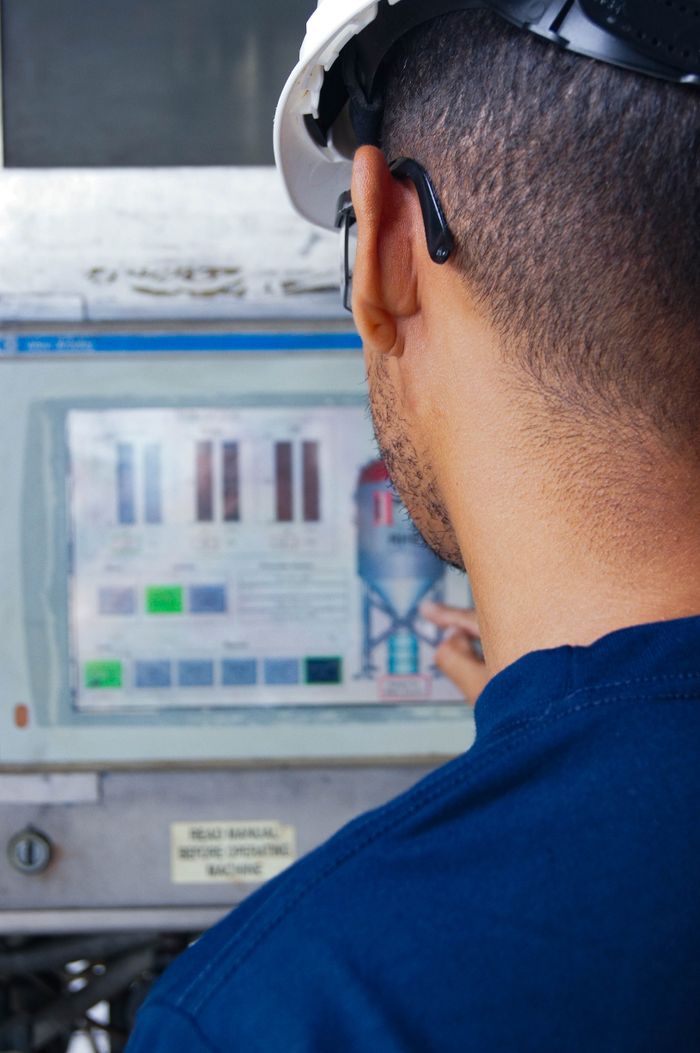 Crafting Captivating Headlines: Your awesome post title goes here Engineer with hard hat working at an industrial control panel, displaying graphs.